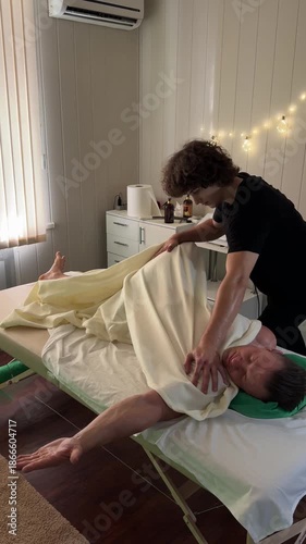 Therapist pressing deeply into shoulder muscles of male client using firm manual technique