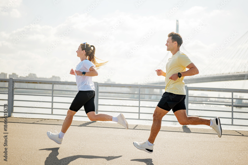 Fototapeta premium Couple jogging along the river during sunny weather