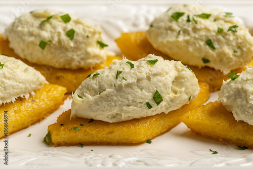 Photos Close up of  baccala mantecato, whipped, creamed salt cod fish spread, is a Venetian appetizer made with dried cod, served on fried polenta croutons