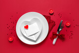 Table setting for Valentine's Day with blank paper card, burning candles and confetti on red background