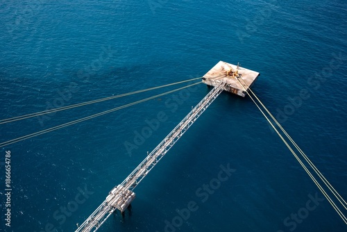 Foto Concrete platform with mooring post and long ropes holding large boat in place