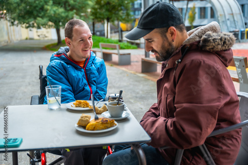 Young man with disability enjoying coffee with friend