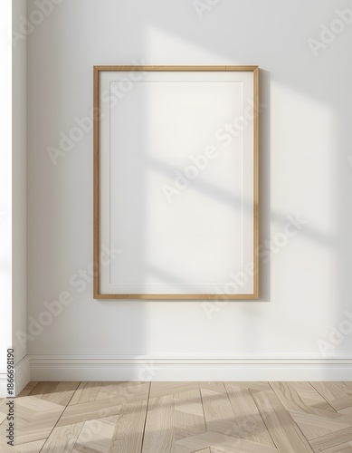 A blank picture frame hangs on a white wall in a room with wooden flooring