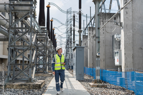 Fotografie Electrical engineer walking through high voltage power substation while inspecting equipment, supporting routine maintenance, safety compliance, and reliable electricity distribution
