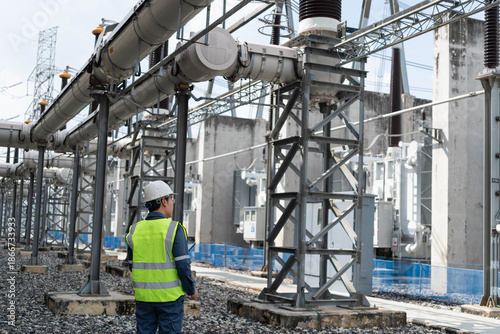 Cuadro en lienzo Professional electrical engineer inspecting outdoor high voltage substation infrastructure and power transformers