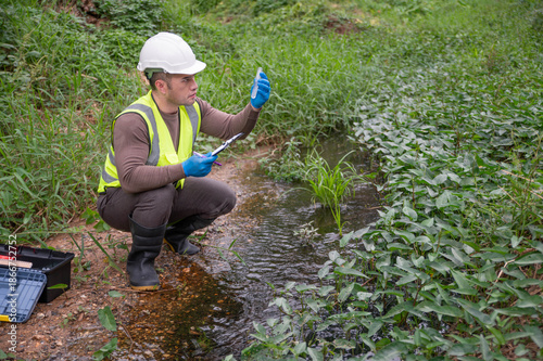 Vászonkép An environmentalist is checking the aquatic life in a small stream to monitor the ecosystem
