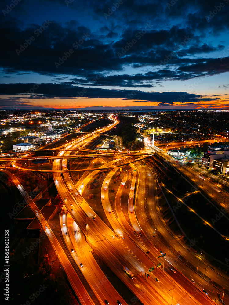 Fototapeta premium Aerial night view of Turcot Interchange in Montreal with glowing highways and city lights at dramatic blue hour. g.