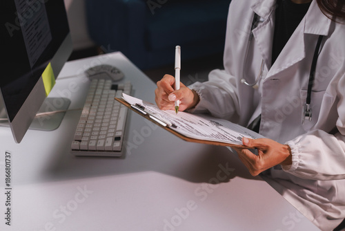 Doctor writing patient report on clipboard at desk