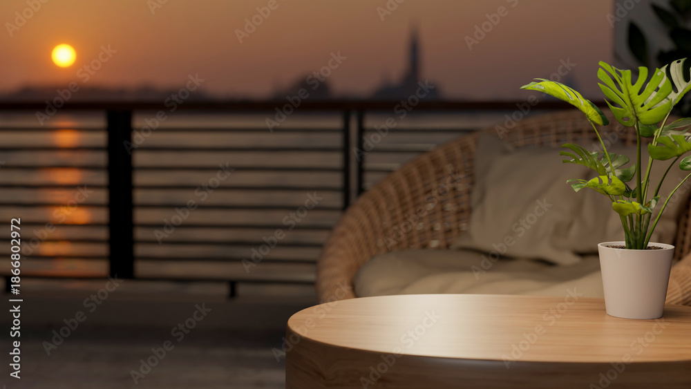Naklejka premium Potted plant on round wooden table and woven sofa chair at balcony or rooftop and sunset above river