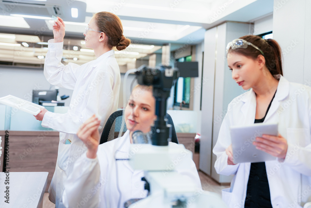 Fototapeta premium Diverse team of female scientists working in busy digital pathology lab. Researchers analyzing histology slides using microscope, tablet, and visual inspection for medical diagnosis.
