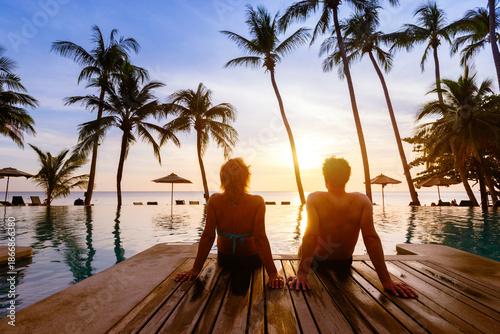 silhouette of couple sitting near swimming pool at beach hotel resort, summer holidays, honeymoon vacation travel to tropical country