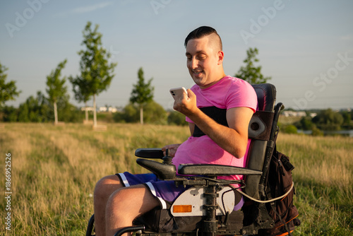 : Outdoor lifestyle scene of a wheelchair user holding a smartphone under bright sunlight.