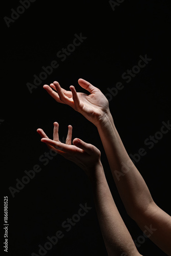 Wallpaper Mural Two feminine hands reaching upward in a soft, open gesture against a dark background, lit to accentuate form and emotion Torontodigital.ca