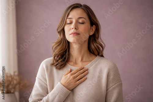 Woman with eyes closed and hand on chest in soft neutral studio setting, gentle beige tones expressing grounding, emotional awareness, calm breathing, and self regulation, suitable for mental wellness