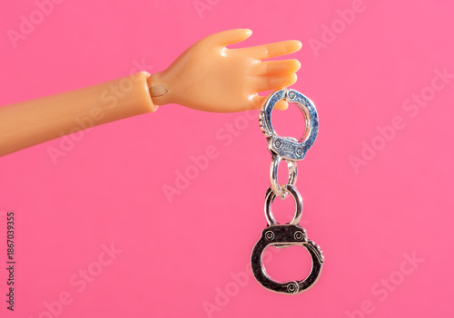 Mannequin Hand Holding Handcuffs on Pink Background
