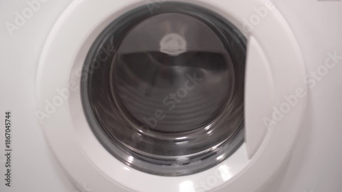 Foamy soap suds churning around shoes in washing machine drum, creating dynamic bubble patterns. Dense white foam envelops footwear during intense cleaning cycle.