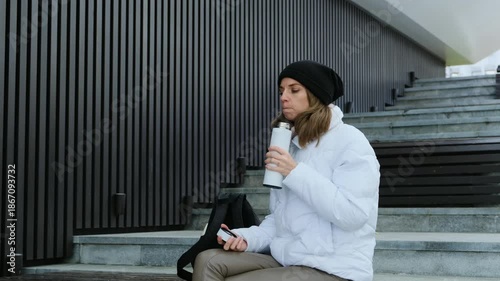 Beautiful Girl in White Winter Jacket Drinking Hot Tea from Thermos. Cold Weather Coziness.