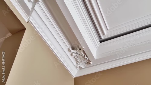 Ornate white crown molding accents a light beige ceiling
