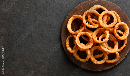 Heap of deep fried onion rings on wooden serving dish