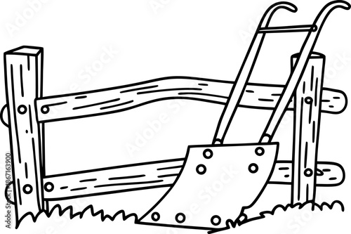 Traditional hand plow leaning against rustic wooden fence on grassy ground