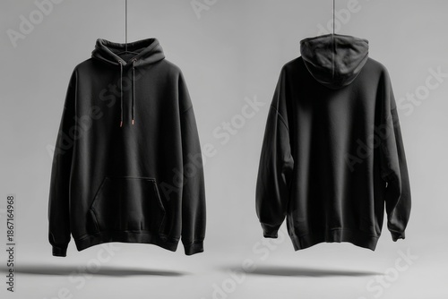 Black hoodie sweatshirt mockup, blank front and back sides displayed on a smooth grey studio surface, isolated clothing template. Oversize hooded apparel, casual streetwear garment for custom design.