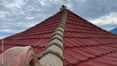 The roof of the traditional building with red tiles and symmetrical lines leading to the peak, shows off the architectural details and texture of the material.
