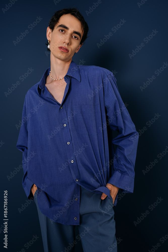 Obraz premium Stylish man poses confidently in blue ensemble against a solid backdrop