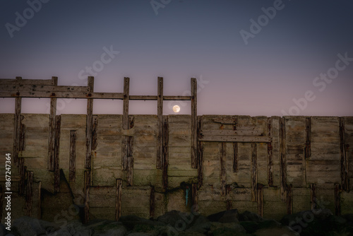 Photos Full Moon Rising Above Coastal Sea Defence at Twilight