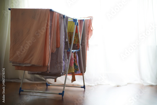 Canvas-taulu Bright Laundry Room with Clothes Drying on Indoor Drying Rack by Sunny Window