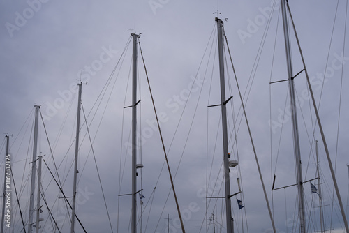 фотографія Sailboat masts in marina with ropes and rigging against cloudy sky