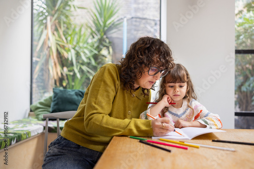 Mom teaching daughter how to write at home