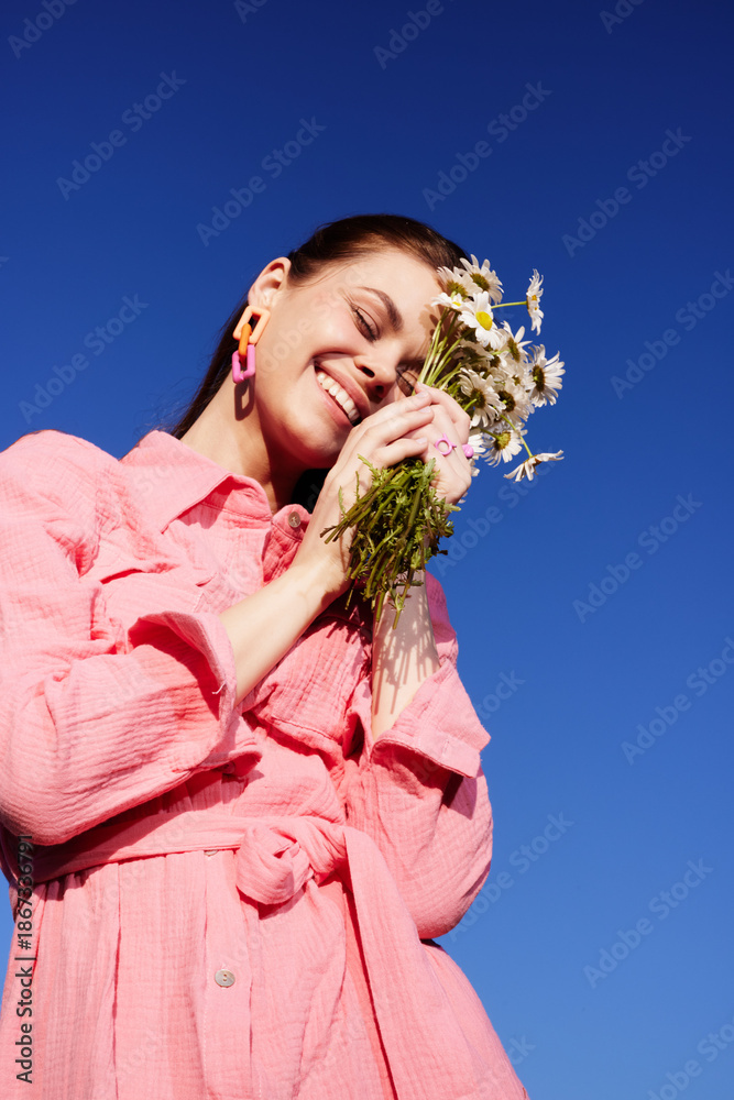 Φωτογραφία Cheerful young woman holding a bouquet of daisies against a clear blue sky, wear