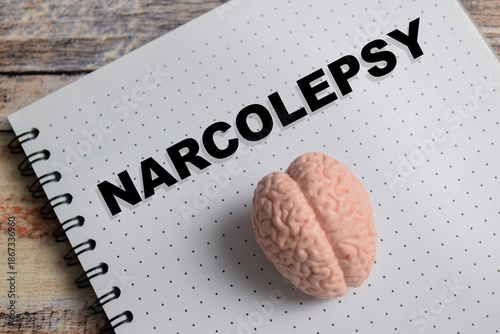 Photos Concept of narcolepsy write on book isolated on Wooden Table.