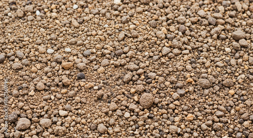 Close-up of a mix of small pebbles, dirt, and gravel, presenting a textured, uneven surface in shades of brown and gray