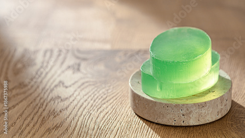 Fotografie Green translucent aloe vera soap bars on round travertine stone podium