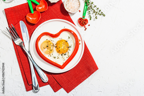 Heart-shaped fried egg served with toasted bread. Romantic art food idea for Valentine's breakfast