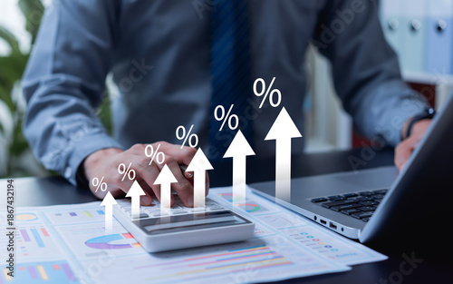 Businessman calculating interest rate impacts with percentage graph and upward arrow, analyzing investment growth, profits, dividends, long-term financial planning, and tax calculations.