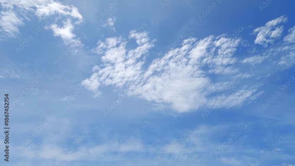 Obraz premium Beautiful white clouds in a clear blue sky. Bright blue sky background with soft clouds. The sky is filled with fluffy white clouds.