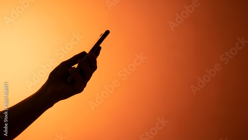 Silhouette of a hand pointing upwards against an orange background