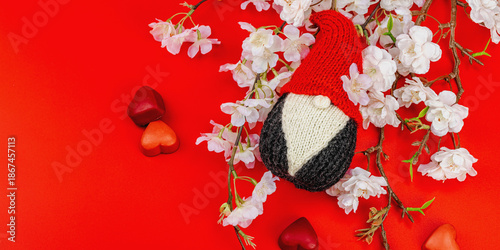Minimalist spring greeting card with knitted gnome and blooming cherry branches