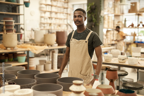 Tableau sur toile Young African potter standing by a table in a ceramics workshop
