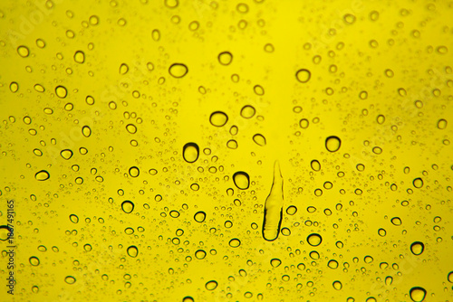 Water drops on glass with yellow background