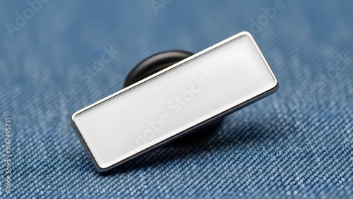 Blank rectangular enamel lapel pin with a polished silver metal border resting on a textured blue denim fabric surface ready for custom branding or promotional design applications