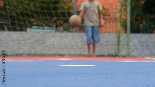 Boys playing soccer barefoot. Kicking the ball from the penalty spot into the goal on an outdoor futsal field.