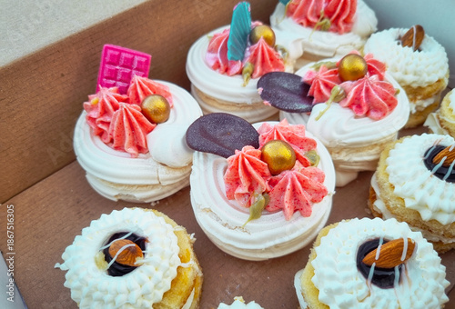 Top view of still life with different types of colorfully decorated cupcakes in a paper box