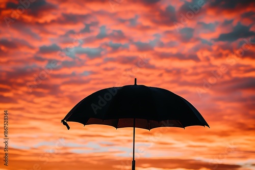 Silhouette of an umbrella against a vibrant sunset sky high resolution image