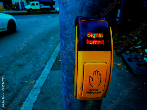 This is a yellow and big signal request device with german words on an early evening in Germany.