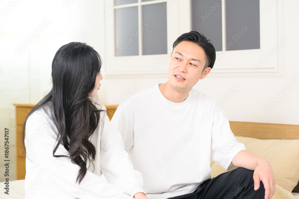 Fototapeta premium 夜の寝室で笑顔で会話をする日本人男女