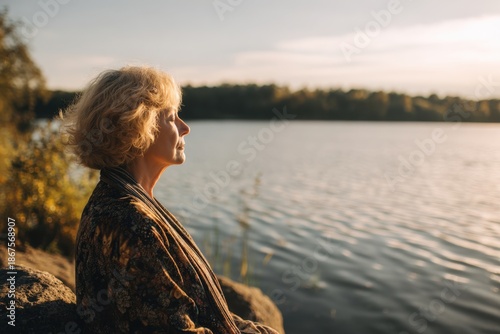 Elderly Woman Relaxing by Tranquil Lake During Golden Hour Serenity.