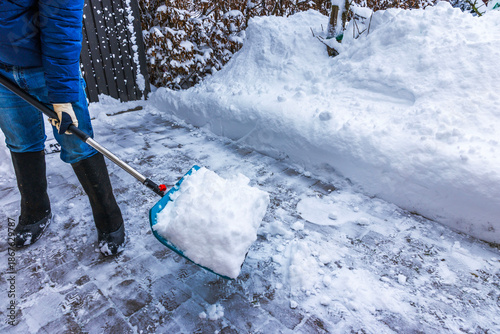 Close up view of person removing snow with snow shovel on icy walkway during winter. Sweden.
